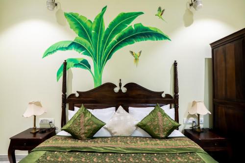 a bedroom with a bed with a large plant on the wall at Dera Jaipur Homestay in Jaipur
