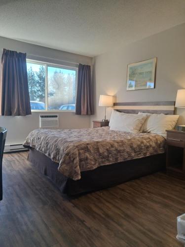 a hotel room with a bed and a window at Bon Voyage Inn in Prince George