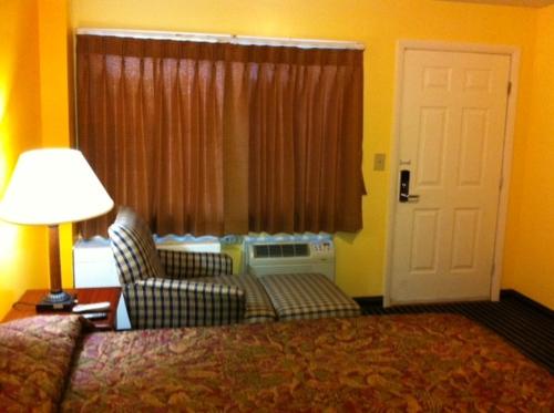 a hotel room with a bed and a chair and a window at Ashford Motel in Ashford
