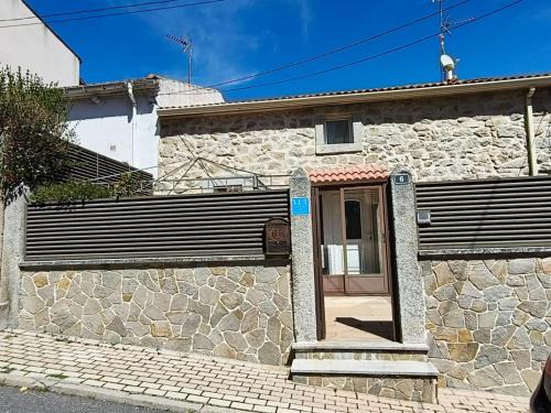 a stone house with a door and a stone wall at Casa Buenavista in Las Navas del Marqués