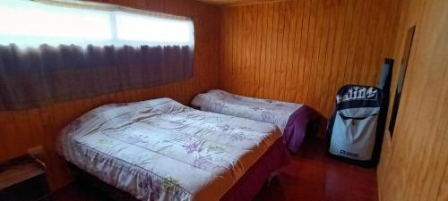 a small bedroom with two beds and a window at Casa Surf Tongoy in Tongoy