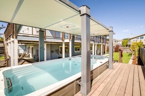 a large hot tub on a wooden deck with an umbrella at Walk to Poplar Beach Cozy Coastal Getaway with Yard in Half Moon Bay