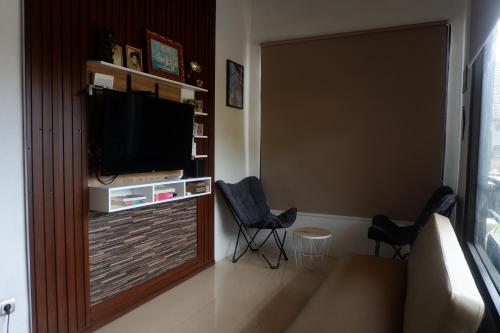 Una sala de estar con dos sillas y un televisor de pantalla plana. en Niang Hostel Penida, en Sampalan