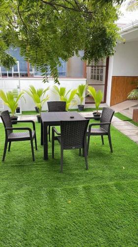 a table and chairs on the grass in a yard at Turtle Inn Dharavandhoo in Dharavandhoo