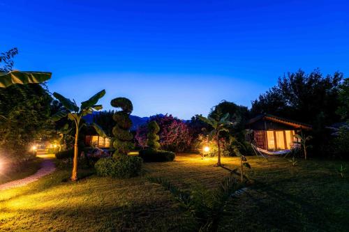 a garden at night with a house in the background at Etenna Beach Bungalows in Cıralı