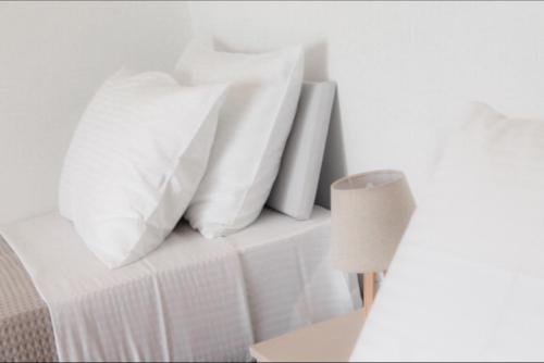 a white bed with white pillows and a lamp at Luxury apartment Reverie in Áyios Yeóryios