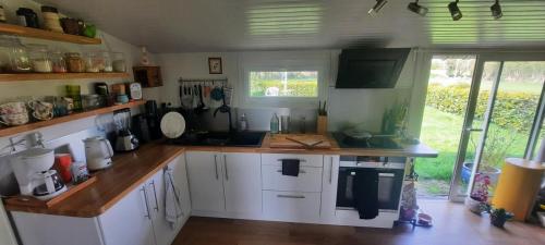 une cuisine avec des armoires blanches et un comptoir en bois dans l'établissement Longère Belle-Isle en terre, à Belle-Isle-en-Terre