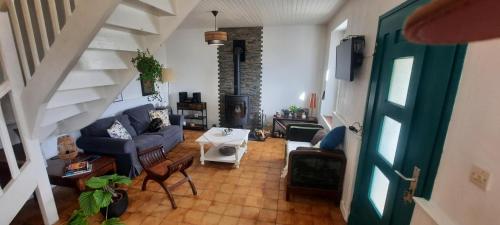 - un salon avec un canapé bleu et un escalier dans l'établissement Longère Belle-Isle en terre, à Belle-Isle-en-Terre