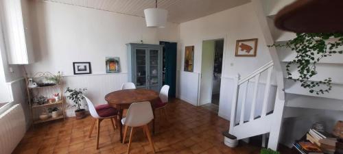 un salon avec une table et des chaises blanches dans l'établissement Longère Belle-Isle en terre, à Belle-Isle-en-Terre
