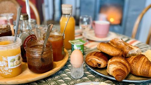 a table with a plate of croissants and jars of honey at Auberge Casa Sana in Pillac