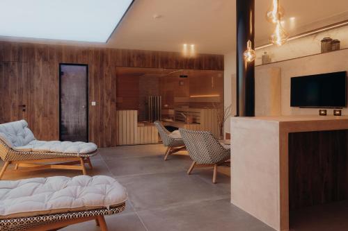 a living room with a tv and a couch and chairs at Au Porte Bonheur in Zwalm