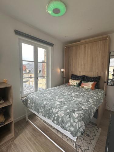 une chambre avec un lit avec une grande fenêtre dans l'établissement Le nid de la cathédrale, à Bayeux