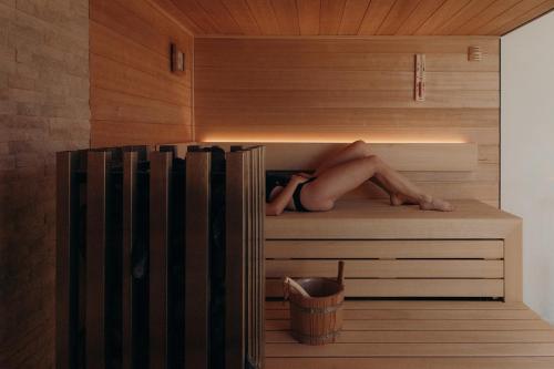 a woman laying on a shelf in a sauna at Au Porte Bonheur in Zwalm