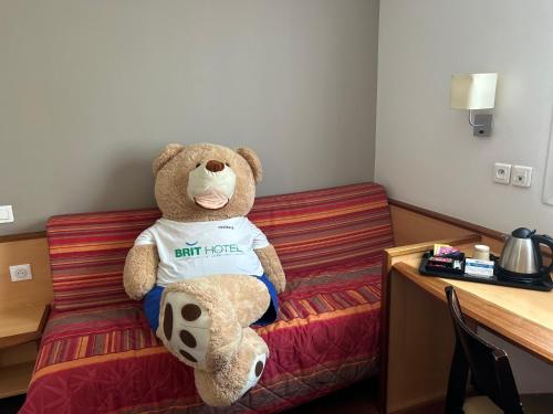 a teddy bear sitting on a bed in a room at Brit Hotel Confort Montauban in Montauban