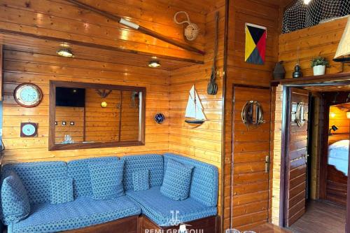 - un canapé bleu dans une chambre dotée de murs en bois dans l'établissement The Boat Central Terrace Retreat 2 Guests, à Honfleur