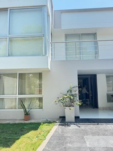 a white house with two potted plants in front of it at Habitación de Lujo a pocos metros del parque de la leyenda in Valledupar