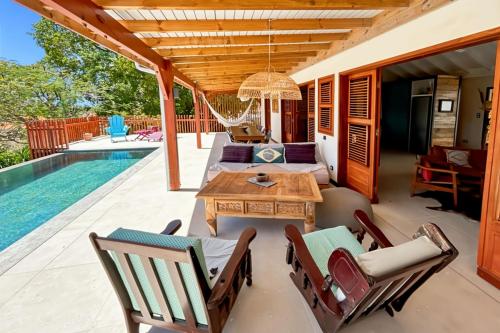 a patio with a table and chairs next to a swimming pool at Villa Tanamera in Grand-Bourg