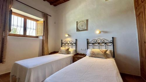 two beds in a room with a window at Casa Can Lluc con piscina, jardín y vista al campo in Sant Miquel de Balansat