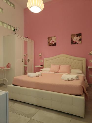 a bedroom with a large bed with pink walls at Pomillo Rooms in Noto