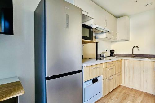 une cuisine avec un réfrigérateur en acier inoxydable et des armoires en bois dans l'établissement Apartment 2 rooms with garden in La Rochelle, à La Rochelle