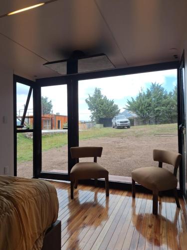 a bedroom with a bed and two chairs and a large window at Pinares de Cacheuta in Las Heras