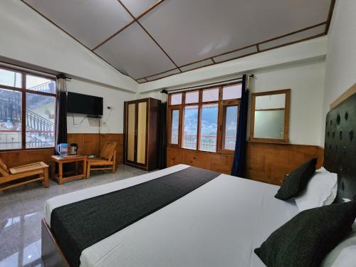 a bedroom with a large bed in a room with windows at Kundan Hotel and Restaurant in Manāli