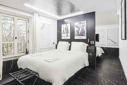 - une chambre noire et blanche avec un grand lit blanc dans l'établissement Divine Couture - Suite Rive Gauche, à Carrières-sur-Seine