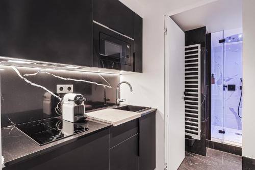 - une cuisine noire et blanche avec un évier dans l'établissement Divine Couture - Suite Rive Gauche, à Carrières-sur-Seine