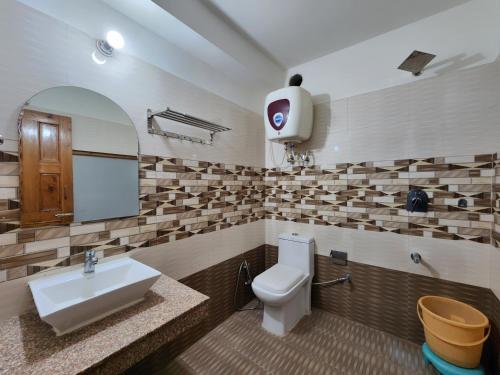 a bathroom with a white toilet and a sink at Kundan Hotel and Restaurant in Manāli