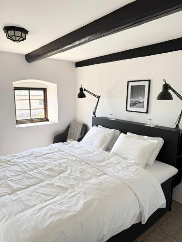 a bedroom with a large white bed with two lamps at Gårdshotellet in Ystad