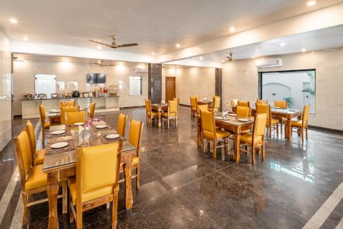 a dining room with wooden tables and yellow chairs at Lime Tree Hotel & One Bed Room Serviced Apartment - Noida Next to Sector 50 Metro with Party Venue in Noida