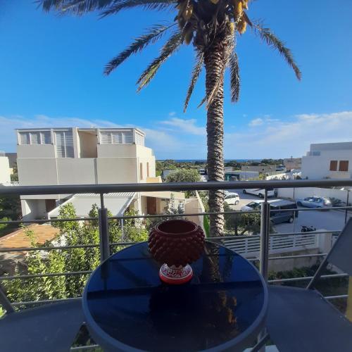 a table on a balcony with a palm tree at Ponente & Maestro Rooms in Favignana