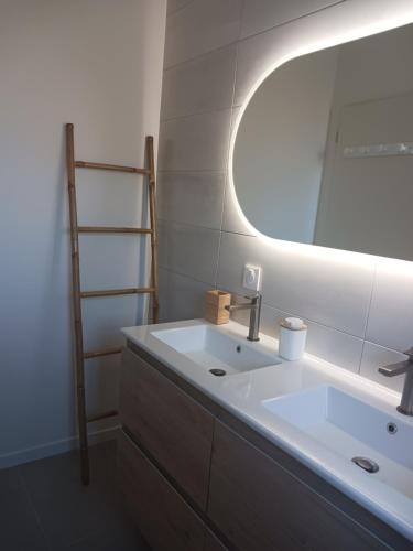 une salle de bain avec un lavabo et un miroir dans l'établissement Santa Monta, à Montalivet-les-Bains