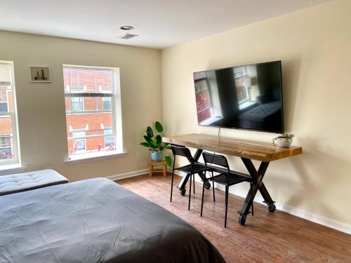 a bedroom with a desk with a flat screen tv on the wall at Cozy Home in the Heart of South Philly in Philadelphia