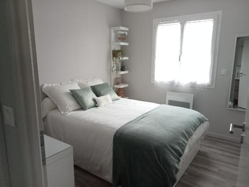 une chambre blanche avec un grand lit et une fenêtre dans l'établissement Santa Monta, à Montalivet-les-Bains