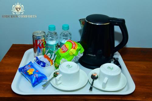 a tray with a coffee pot and cups on a table at Deluxe AC Room by Omicron Comforts-Manyata Tech Park in Bengaluru
