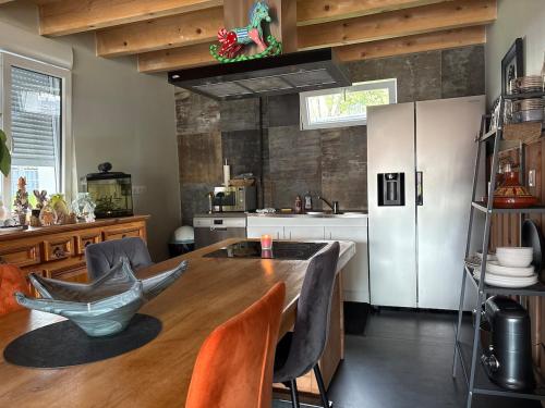 a kitchen with a wooden table and a refrigerator at Maison neuve cocooning 6 personnes Avec Spa et piscine chauffée in Moyenmoutier