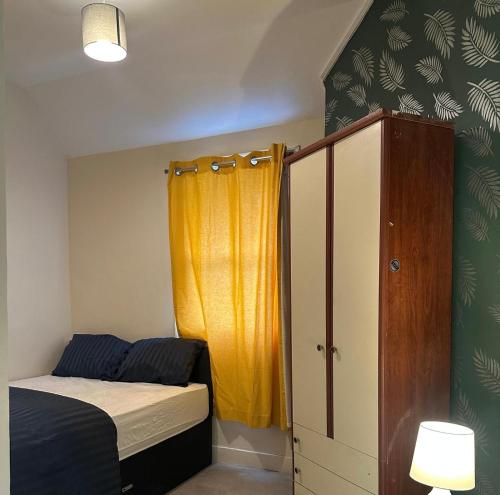a bedroom with a bed and a yellow curtain at Parkend Room Stays in Oxford