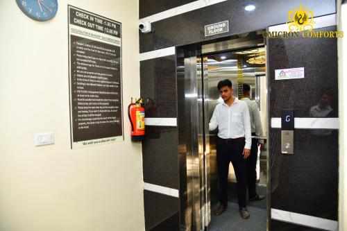 a man standing in an elevator in a building at Deluxe AC Room by Omicron Comforts-Manyata Tech Park in Bengaluru