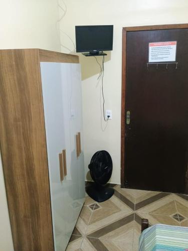 a room with a door and a chair and a television at Pousada Amigu's in Pontal do Paraná