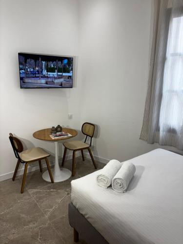 une chambre avec un lit, une table et une télévision dans l'établissement La Petite Arlésienne, à Arles