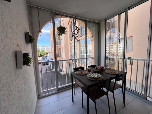 Cette chambre dispose de fenêtres et d'un balcon avec une table et des chaises. dans l'établissement Charmant T2 à 200m plage, à Sète