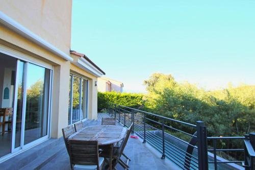 d'une terrasse avec une table et des chaises en bois sur un balcon. dans l'établissement Peaceful villa with pool and garden - 5 minutes from Cannes beaches, à Cannes