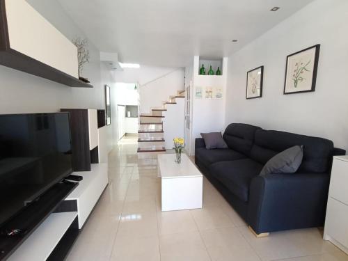 Una sala de estar con un sofá azul y una escalera. en Weisshorn Bungalow 40, en Maspalomas