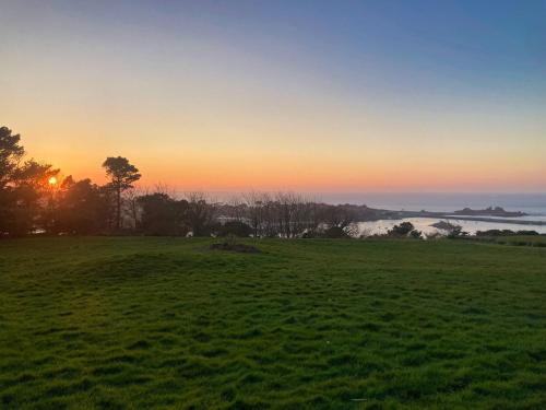 un champ avec le coucher du soleil en arrière-plan dans l'établissement Ker Wind - panoramic sea view house Primel 8-10p, à Plougasnou