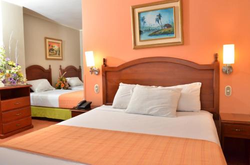 una camera d'albergo con due letti e pareti arancioni di Grand Hotel Americano a Machala
