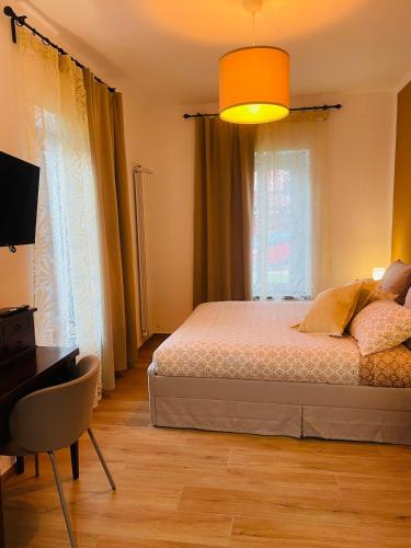 a bedroom with a bed and a desk and windows at Airport Flower Rooms in Ronchi dei Legionari
