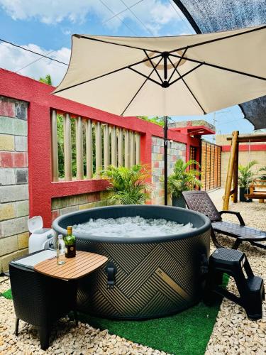 a hot tub in a yard with an umbrella at Cabaña La Roca in San Antero