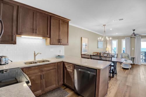 a kitchen with wooden cabinets and a dining room at Surf Song S1 in Fort Morgan