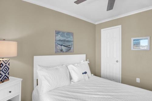 a white bedroom with a bed with white pillows at Surf Song S1 in Fort Morgan